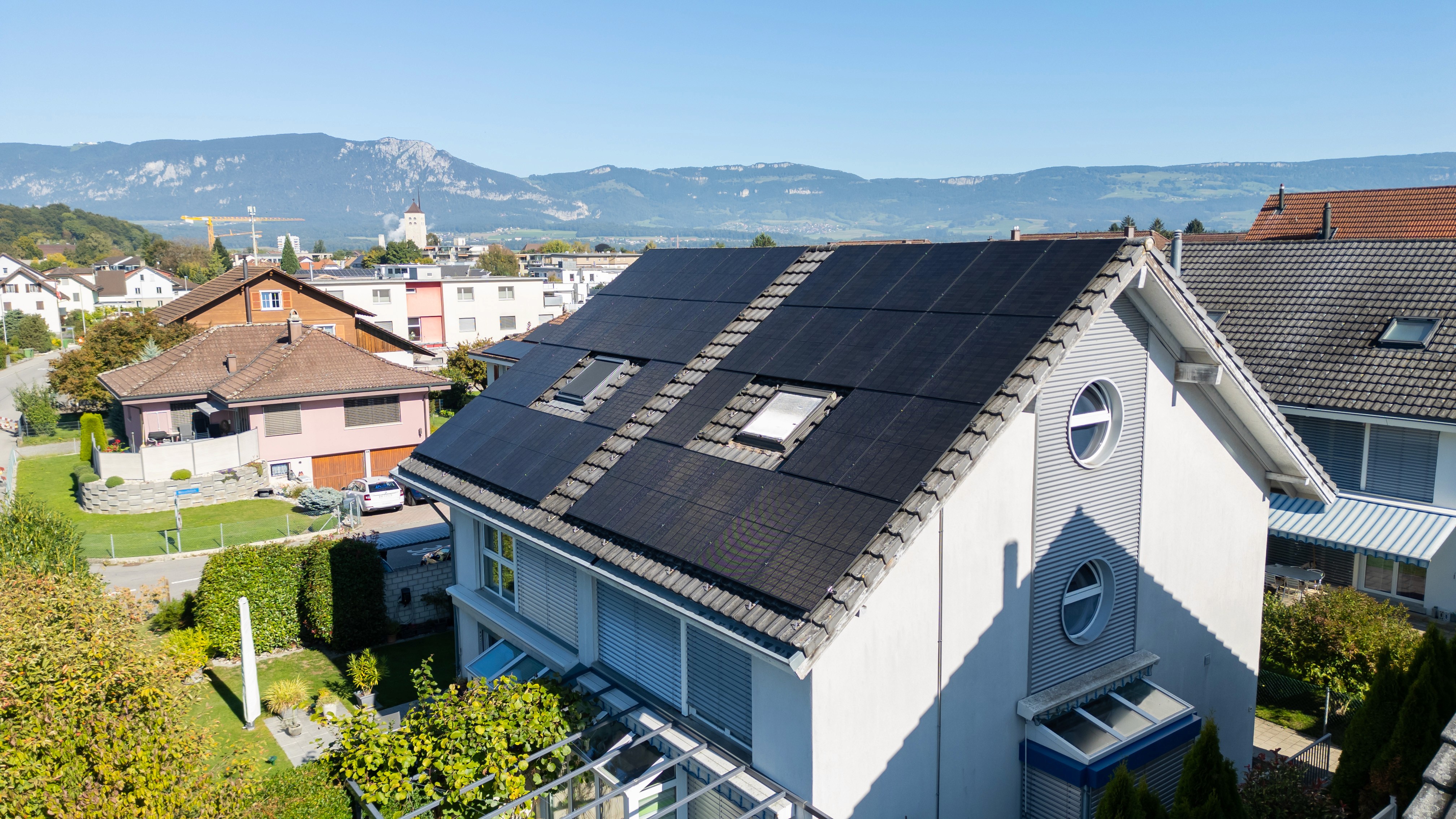 Solarmodule über die gesamte Dachseite eines Wohnhauses, im Hintergrund die Jurakette